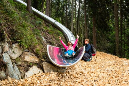a man and a girl sitting on a slide at Wanderhotel Kirchner in Bramberg am Wildkogel