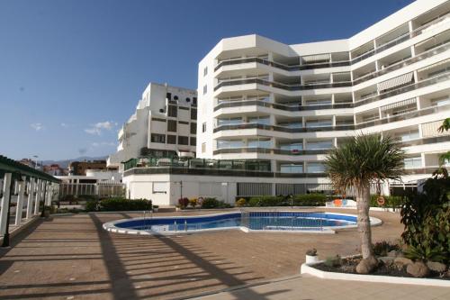ein großes weißes Gebäude mit einem Pool davor in der Unterkunft APARTAMENTO EN EL MEDANO - ESTRELLA DEL MAR in Granadilla de Abona