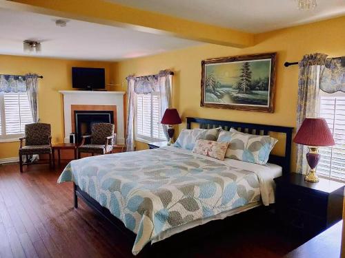 a bedroom with a bed and two chairs and a fireplace at Butterfly Manor in Niagara Falls
