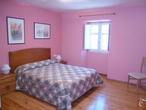 a bedroom with pink walls and a bed and a window at Hostal Betelu in Betelu