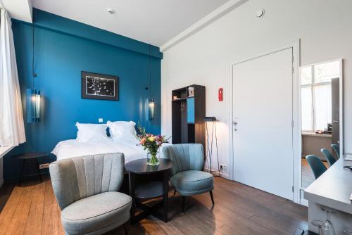 - une chambre avec des murs bleus et un lit avec une table et des chaises dans l'établissement Zakske13 - Design Boutique B&B in Bruges city centre, à Bruges