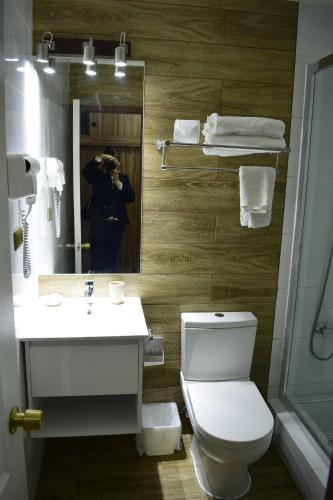 a person taking a picture of a bathroom with a toilet at Apart Hotel Y Cabanas Vegasur in La Serena
