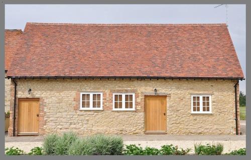 a brick house with two doors and a red roof at Court Farm Barns in Warborough