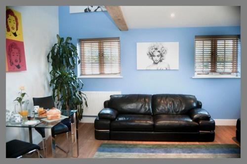 a living room with a black leather couch and a table at Court Farm Barns in Warborough