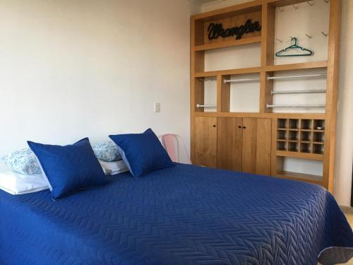 uma cama azul com almofadas azuis num quarto em Séptimo Día em Tandil