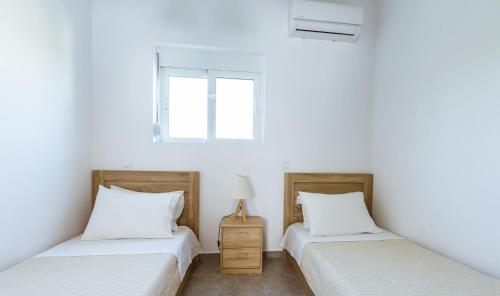 two beds in a room with white walls at Martimi Apartments - 200M from Drapanias Beach - Pool - Hot Tub - Sauna - BBQ in Kissamos