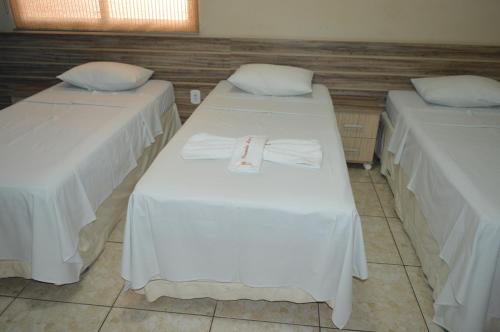 a room with two beds with white sheets at Pousada Ayrumã in Itapipoca
