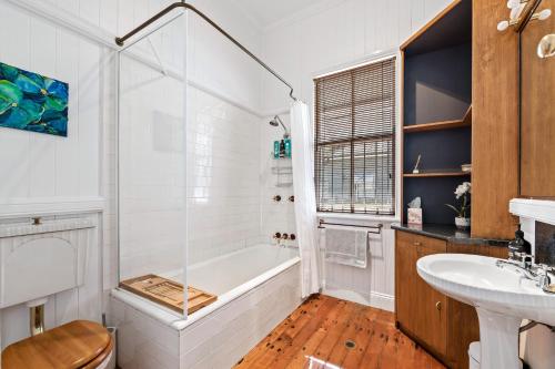 un bagno bianco con vasca e lavandino di Frangipani House a Toowoomba