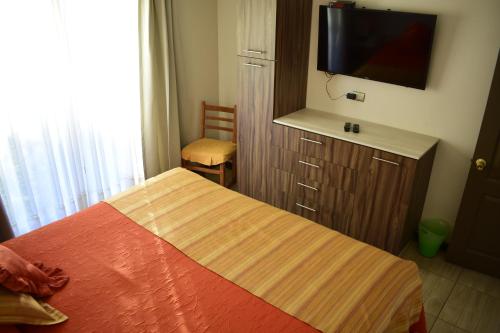 a bedroom with a bed and a flat screen tv at Apart Hotel Y Cabanas Vegasur in La Serena