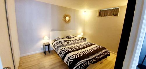 ein Schlafzimmer mit einem Bett mit einer schwarzen und weißen Decke in der Unterkunft Appartement RDC Centre Cabourg in Cabourg