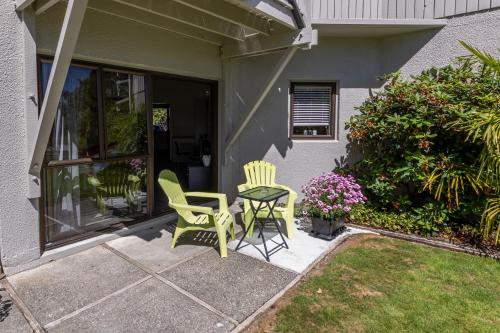 two chairs and a table on the porch of a house at ASURE Explorer Motel & Apartments in Te Anau