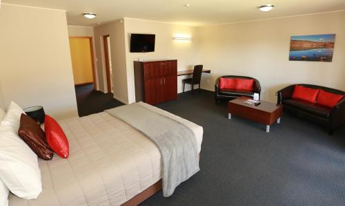 een hotelkamer met een bed, een bank en een stoel bij The Harvest Hotel in Cromwell