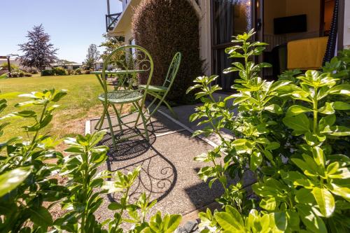 a chair sitting outside of a house with plants at ASURE Explorer Motel & Apartments in Te Anau