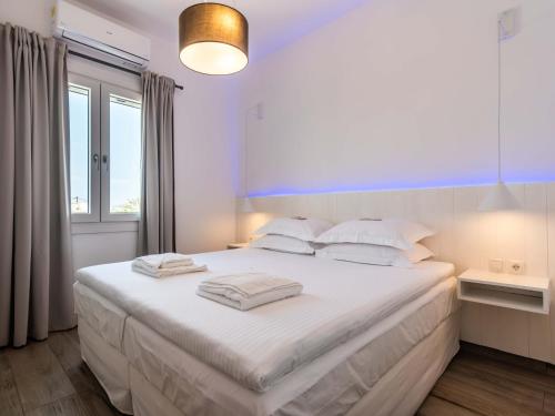 a bedroom with a large bed with white sheets and pillows at White Rock Milos Suites in Adamas