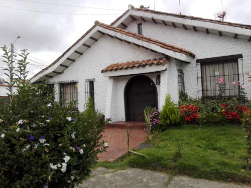 a small white house with a door and flowers at Villa Suite Emanuel in Bogotá