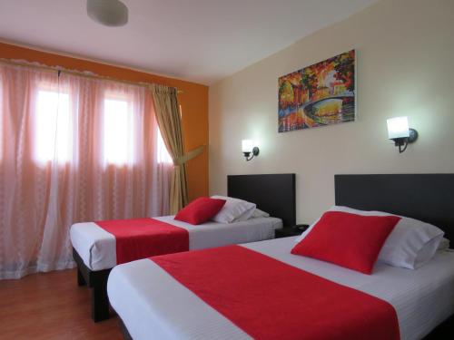 a hotel room with two beds with red and white sheets at Hotel La Herreria Colonial in Popayan