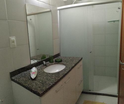 a bathroom with a sink and a mirror and a shower at Lindo apartamento dúplex in Salvador