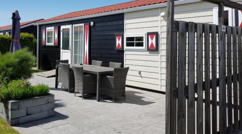 a patio with a table and chairs in front of a house at De Zeeuwse Lûûkjes 1 in Serooskerke