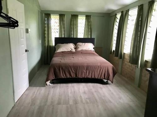 a bedroom with a bed with a brown comforter and windows at Lotopa Tiny House in Lepea
