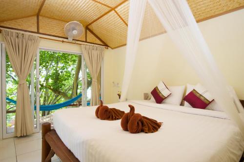 two stuffed animals sitting on a bed in a bedroom at Bubble Bungalow in Koh Tao