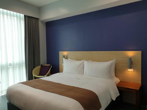 a bedroom with a large bed with a blue wall at Leez Inn Makati in Manila