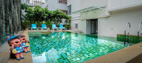 a swimming pool with two dolls sitting next to it at The BluEco Hotel SHA Plus in Kata Beach