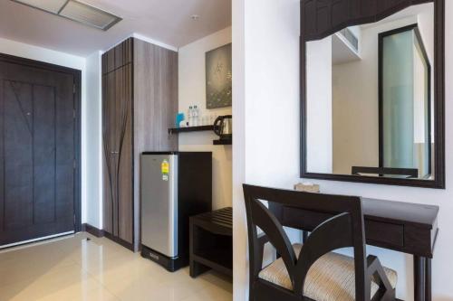 a kitchen with a refrigerator and a chair and a mirror at The BluEco Hotel SHA Plus in Kata Beach