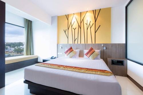 a bedroom with a large bed and a large window at The BluEco Hotel SHA Plus in Kata Beach