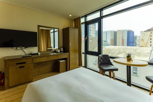 a hotel room with a bed and a large window at Hotel Haema in Jeju