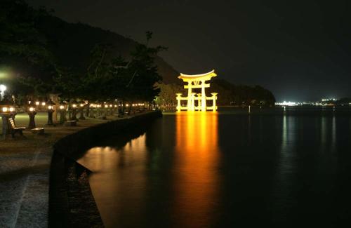 a japanese building on the water at night at Full house Miyajima in Miyajima