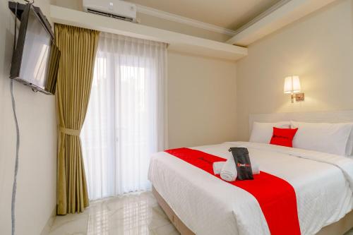 バンドンにあるRedDoorz near Taman Makam Pahlawan Cikutraのベッドルーム(赤い毛布、テレビ付)