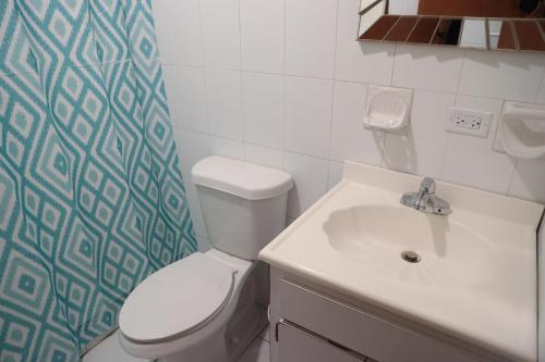 La salle de bains est pourvue de toilettes blanches et d'un lavabo. dans l'établissement Buena Vida Apartments, à Rincon