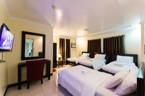 um quarto de hotel com três camas e uma televisão de ecrã plano em Batanes Seaside Lodge & Restaurant em Basco