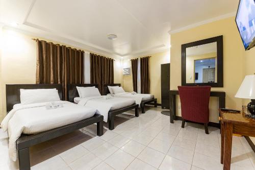 a hotel room with three beds and a mirror at Batanes Seaside Lodge & Restaurant in Basco