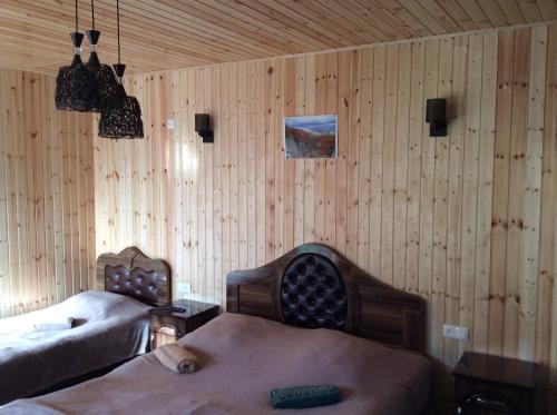 a bedroom with two beds and wooden walls at Taripiri in Ambrolauri