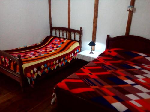 two beds with colorful blankets in a bedroom at La Posada del Cucú in Salento