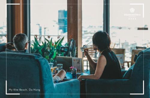 a man and a woman sitting at a table with a laptop at Diamond Sea Hotel in Da Nang