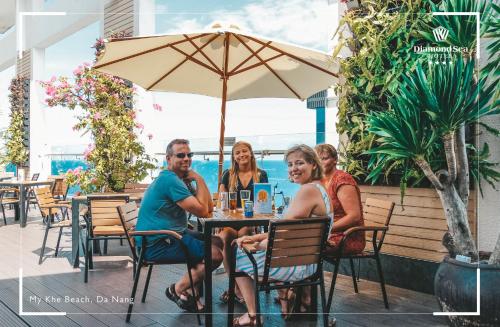 a group of people sitting at a table with an umbrella at Diamond Sea Hotel in Da Nang