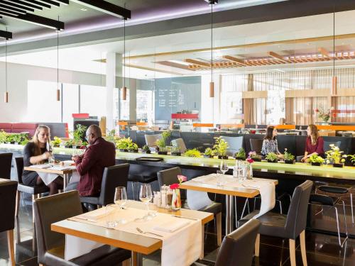 a group of people sitting at tables in a restaurant at Novotel Amsterdam City in Amsterdam