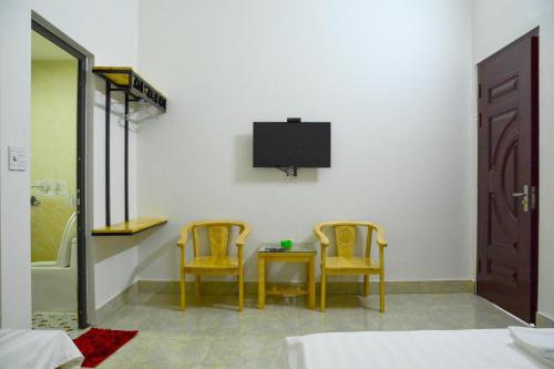 a bedroom with two chairs and a table and a tv at Nhà Nghỉ Ngọc Long in Mộc Châu