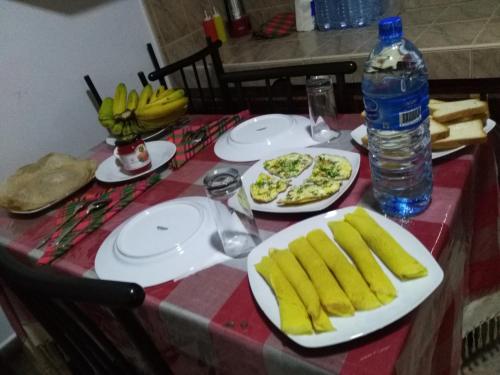 a table with plates of food and a bottle of water at Viyanga Homestay in Ella