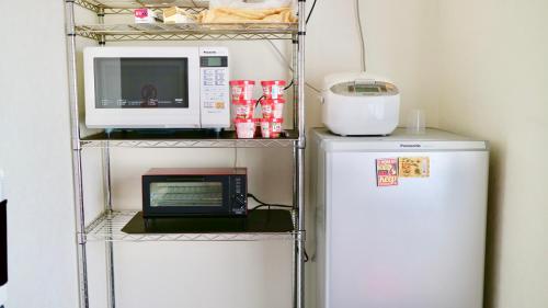 a shelf with a microwave oven and a refrigerator at Benidaruma - Ichigo Daifuku in Kyoto
