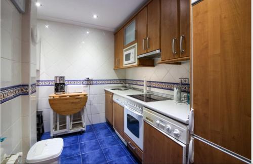 a small kitchen with wooden cabinets and a blue floor at Apartamento Santander zona Tetuán Puertochico in Santander