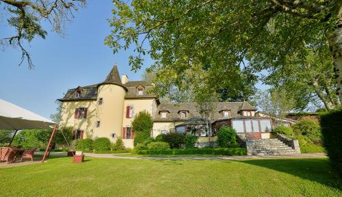 une grande maison avec une pelouse verte en face de celle-ci dans l'établissement Château de Salles, à Vezac
