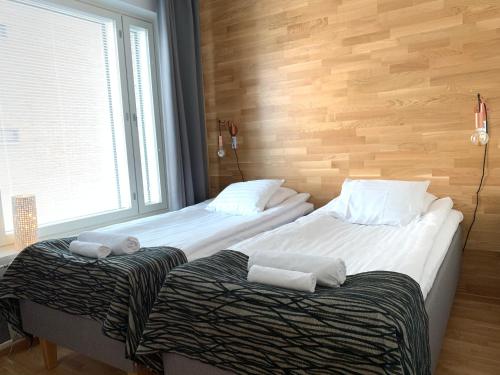 two twin beds in a room with a window at The Harbour Apartments in Jyväskylä
