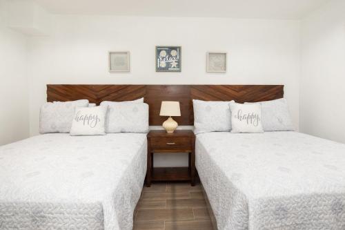 two beds in a room with white sheets at La Casa de Paz Hotel in San Pedro