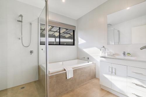 a bathroom with a shower and a tub and a sink at Easy Living Bayside Accommodation in Tootgarook
