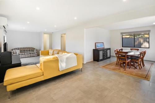 a living room with a yellow couch and a table at Easy Living Bayside Accommodation in Tootgarook