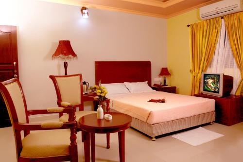 a bedroom with a bed and a table and a chair at Devasura inn in Guruvāyūr