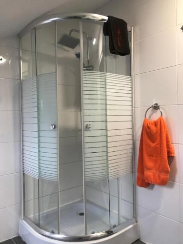 y baño con ducha de cristal y toalla de color naranja. en Pension Haus Baron 4 Mühlheim, en Mühlheim am Main